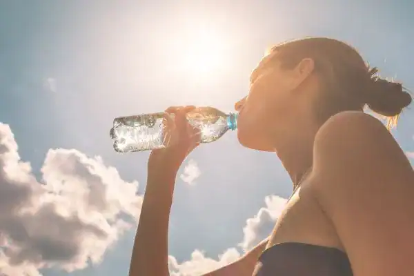 Hydration: The Secret Ingredient for a Toned Stomach and Enhanced Fitness 3 Image of woman drinking water to hydrate Hove after run.